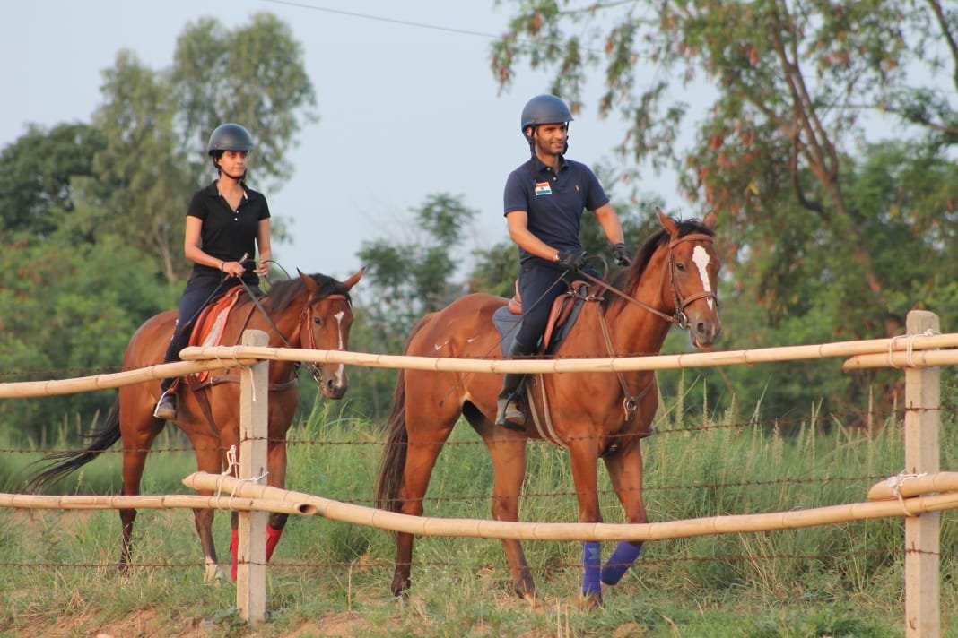 Two riders walking the paddock fence line